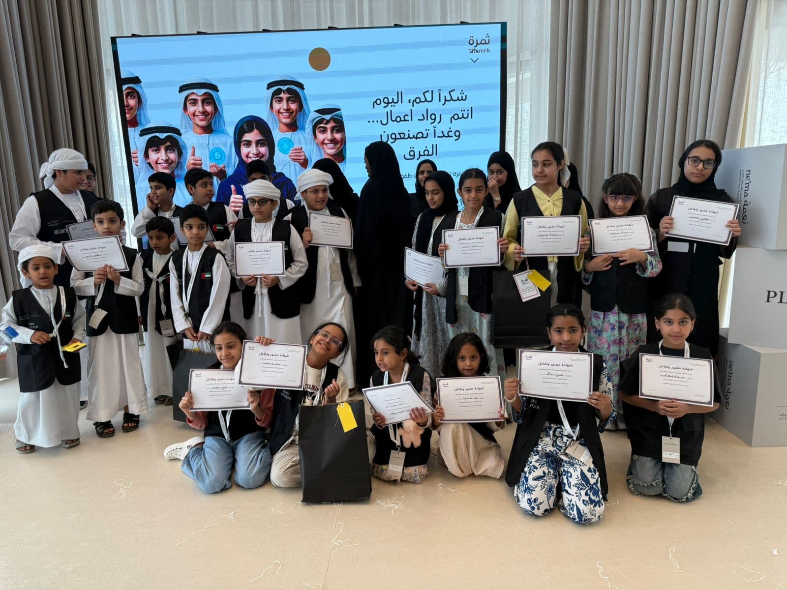 A large group of children holding certificates at a community program